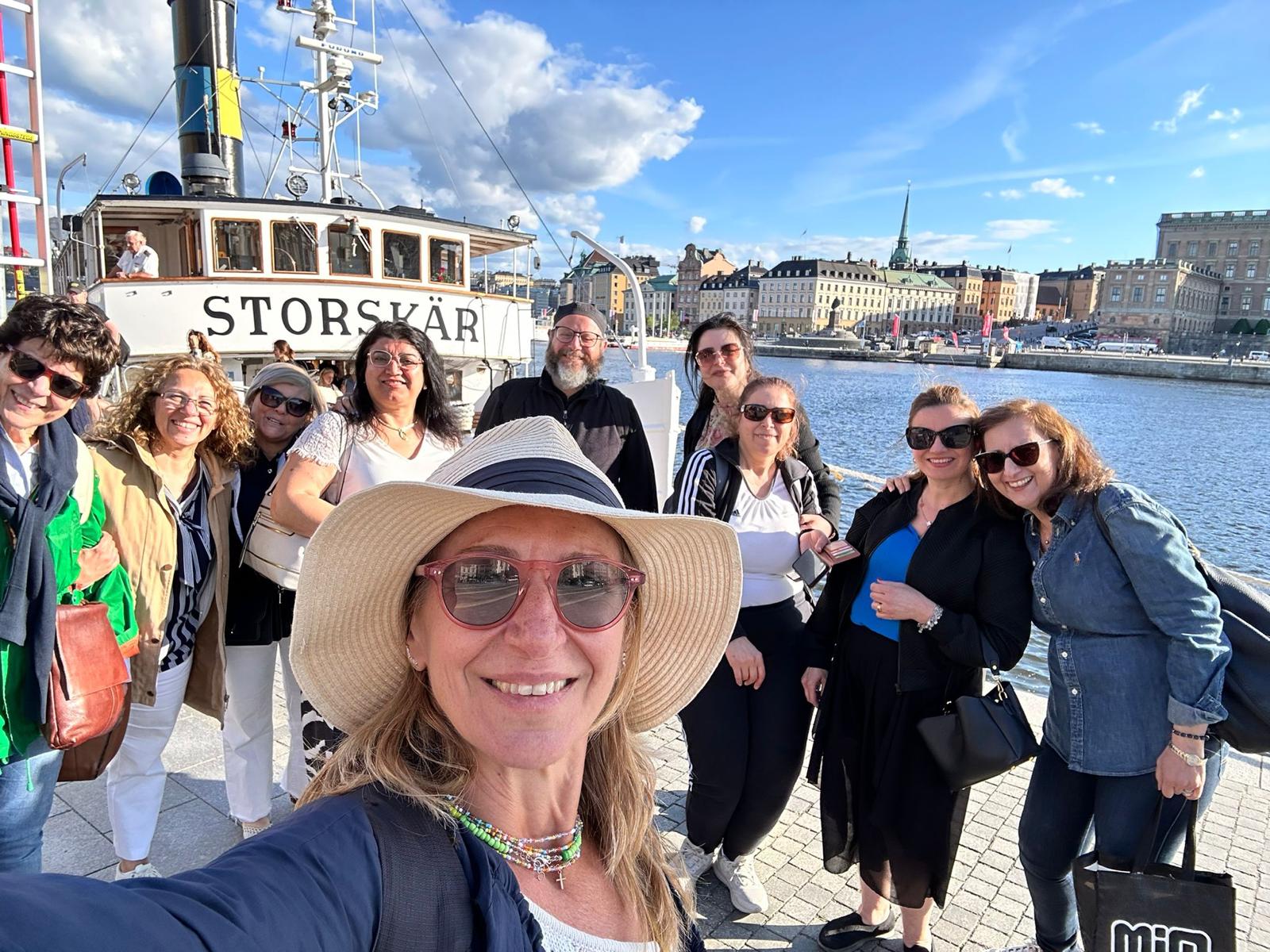 Glada kvinnor på kajen framför ångbåten Storskär i Stockholm en solig dag