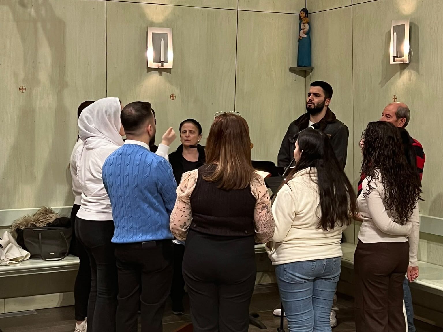 Körmedlemmar står i en ring kring notstället och övar i kyrkan