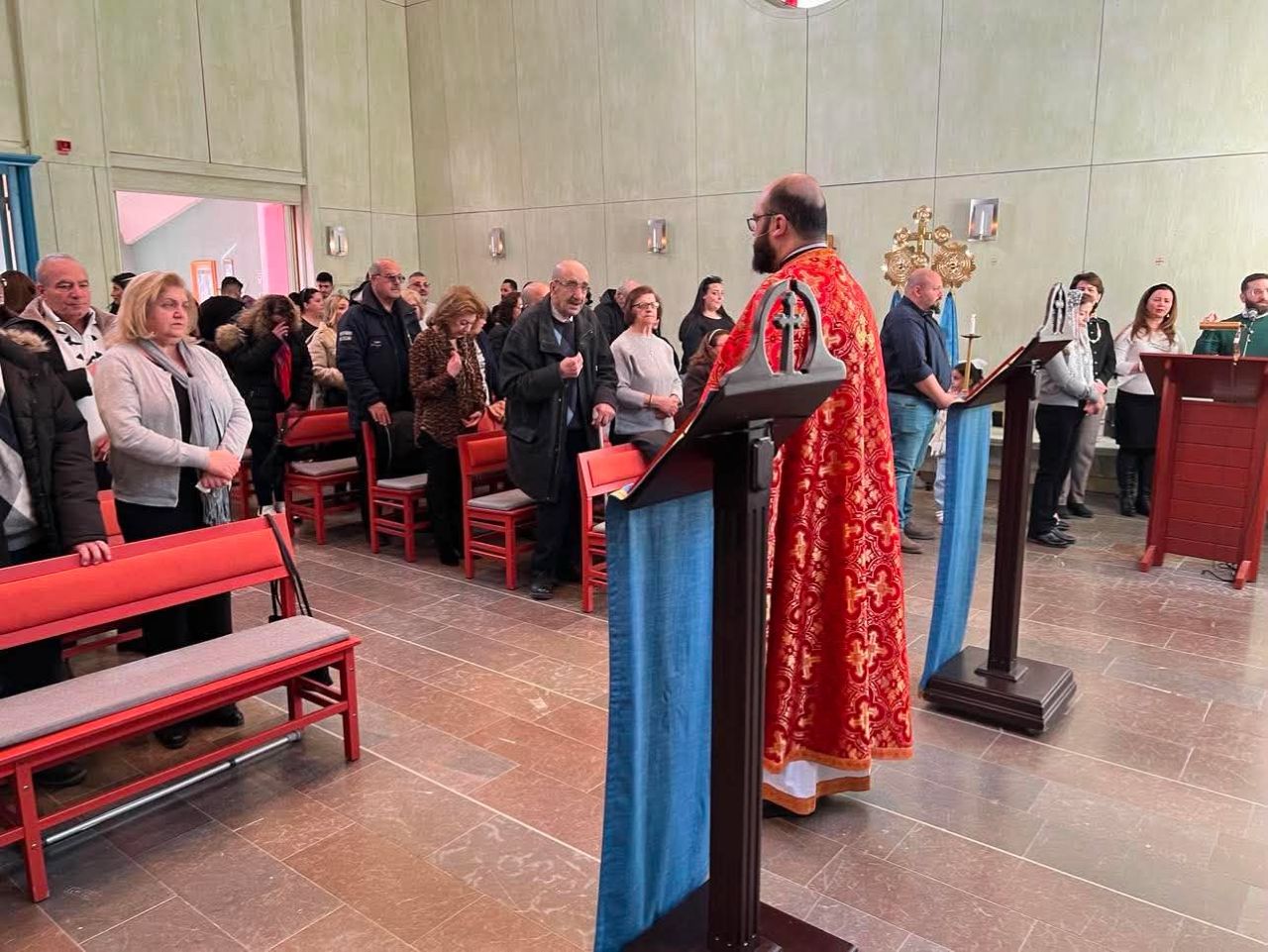 Präst vid predikstolen med församlingen stående i kyrkan