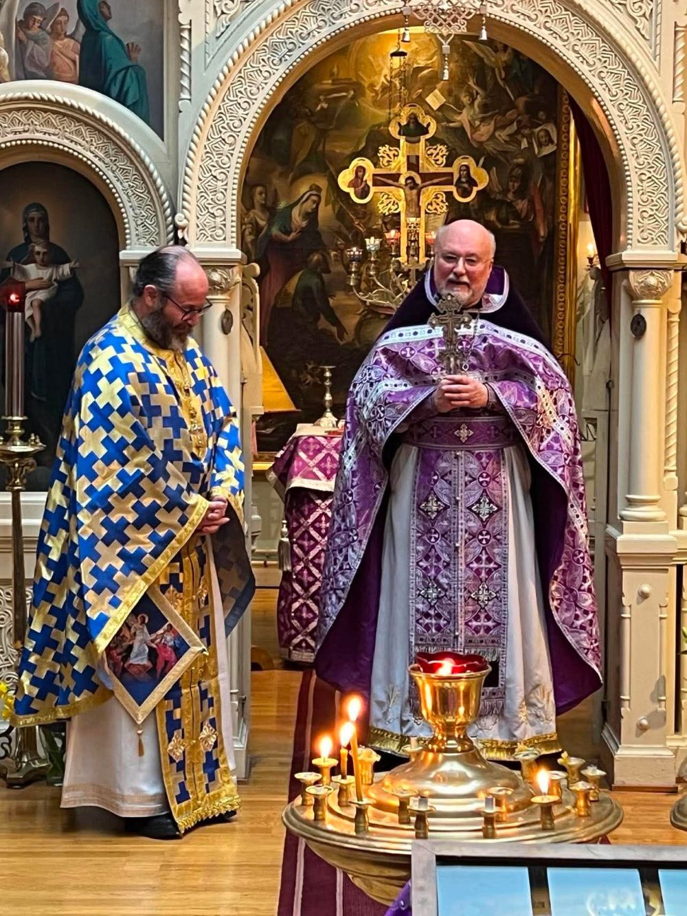 Två präster i liturgiska skrudar vid ljusbäraren