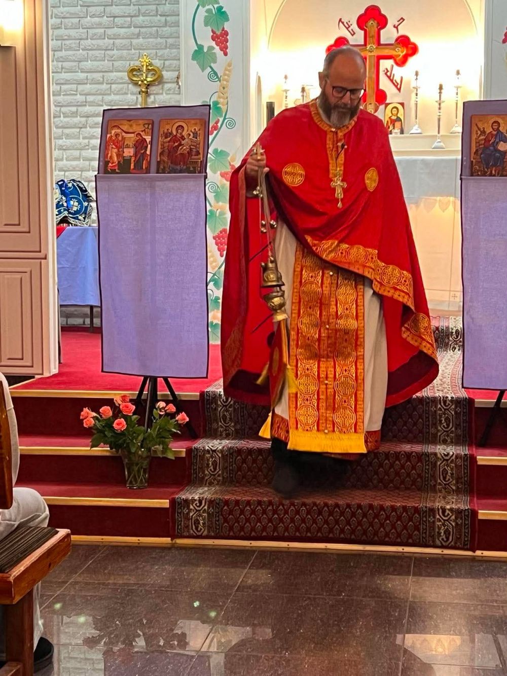 Präst i röd skrud med rökelsekar under liturgin