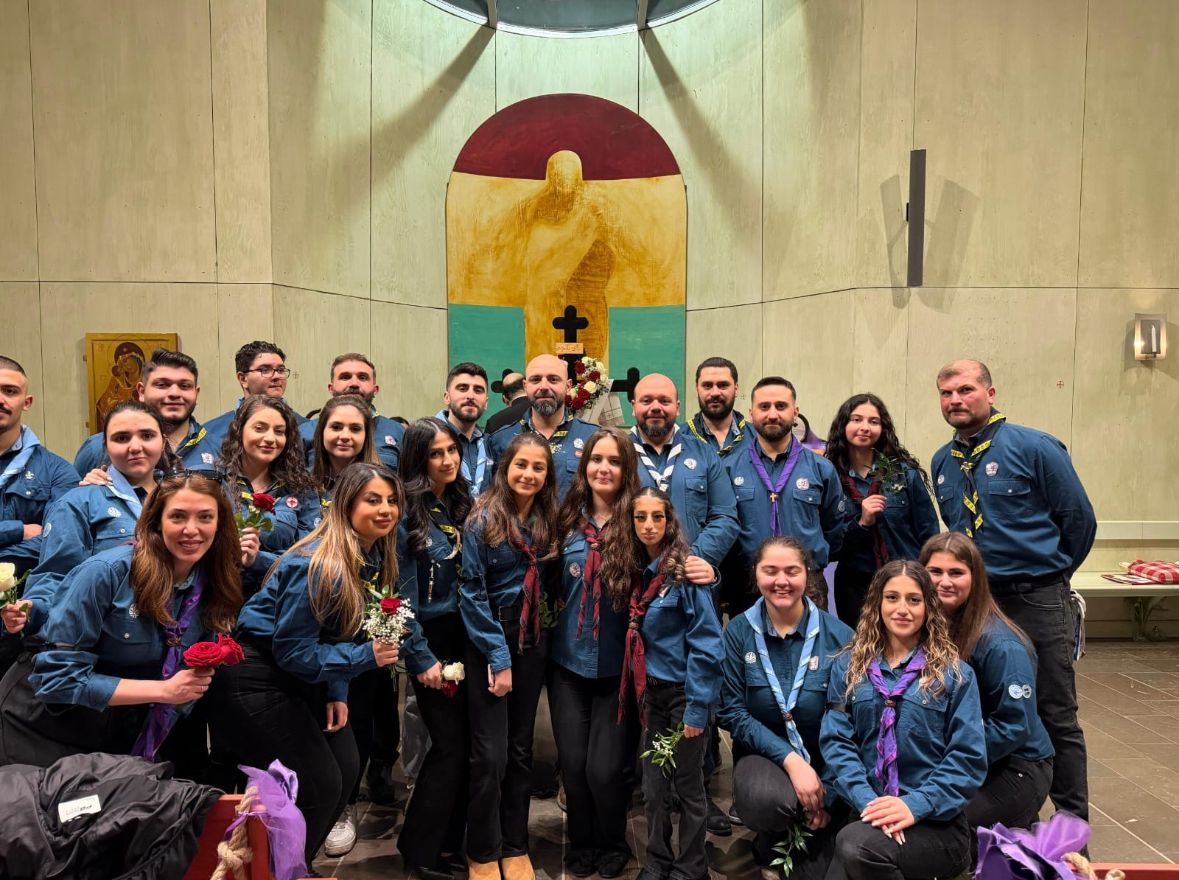 Scoutkårens medlemmar i blå uniformer samlade i kyrkan med rosor i händerna